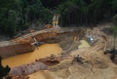 Two helicopters circle about an illegal mining camp in Brazil.
