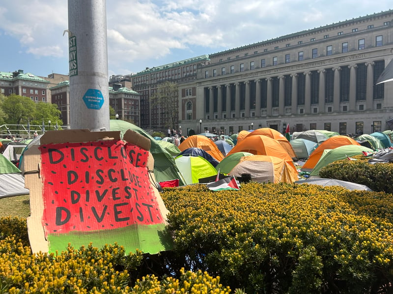 A picket sign, urging Columbia University's divestment from Israel, sits outside of a pro-Palestine encampment on the school's lawn.