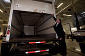 A Canadian police officer wearing a suit opens the back of a nearly empty delivery truck.