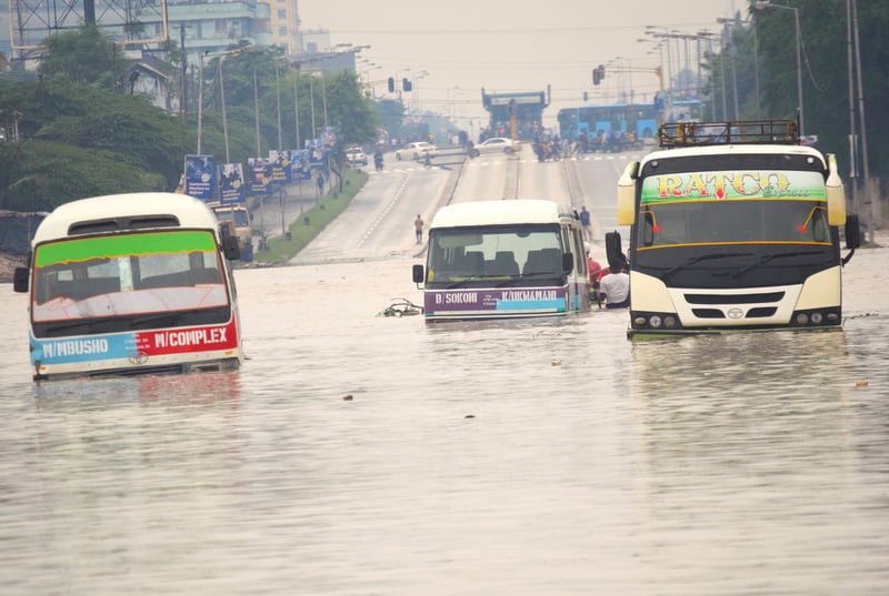 Three buses partially submerged under water on a flooded street in Tanzania.