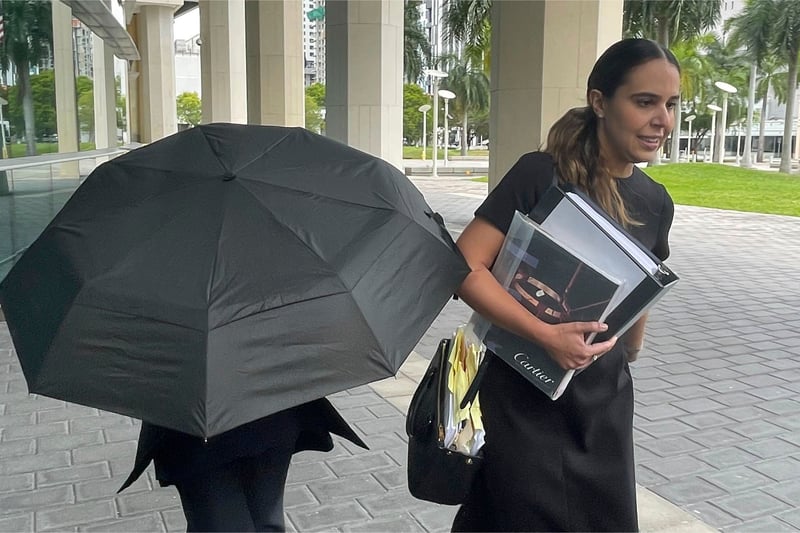 A woman hides behind an umbrella while walking with her attorney.
