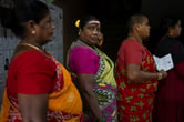 Indian women in saris stand in line to vote.