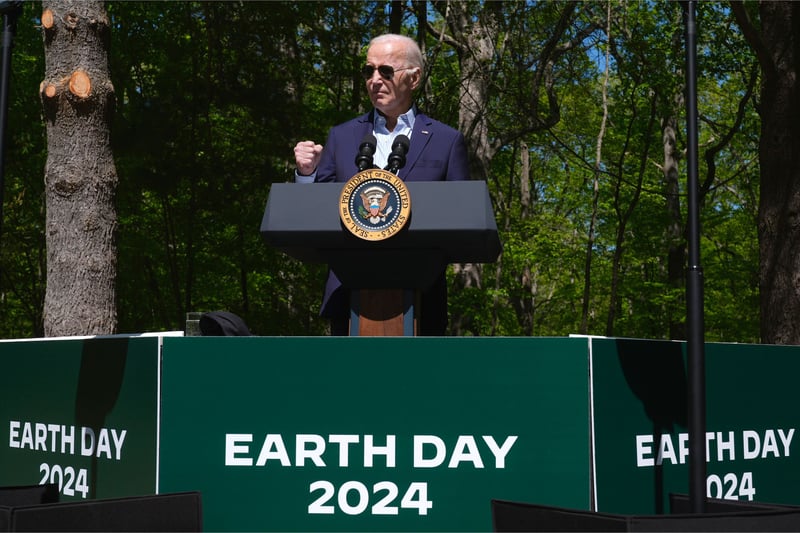Joe Biden speaks from behind a podium and three poster boards that read "Earth Day 2024."