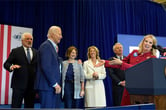 Joe Biden stands on stage with several members of the Kennedy family.