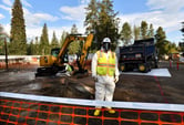 Three workers wearing safety vests and personal protective equipment work in an asbestos cleeanup site.