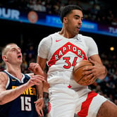The Toronto Raptors' Jontay Porter secures a rebound in front of the Denver Nuggets' Nikola Jokic during an NBA game.