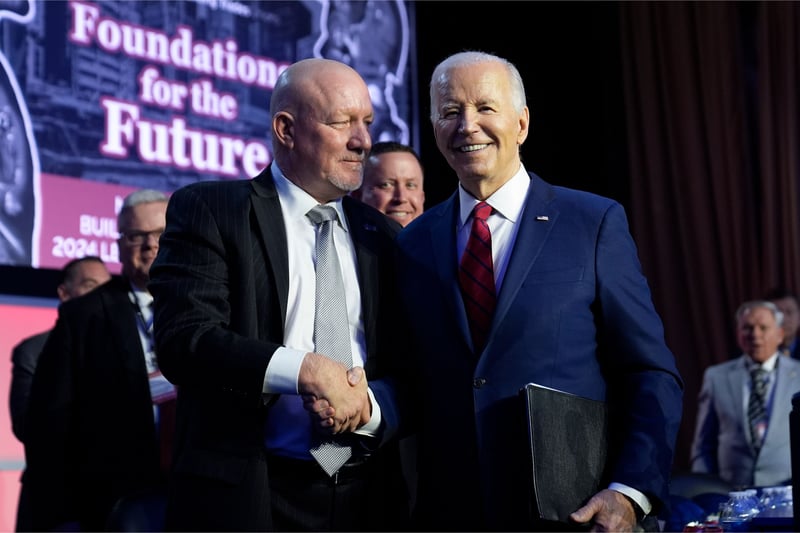 Sean McGarvey and Joe Biden shake hands while standing on stage during an event.
