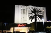 The Tropicana Las Vegas Hotel illuminated at night with a palm tree in the foreground.