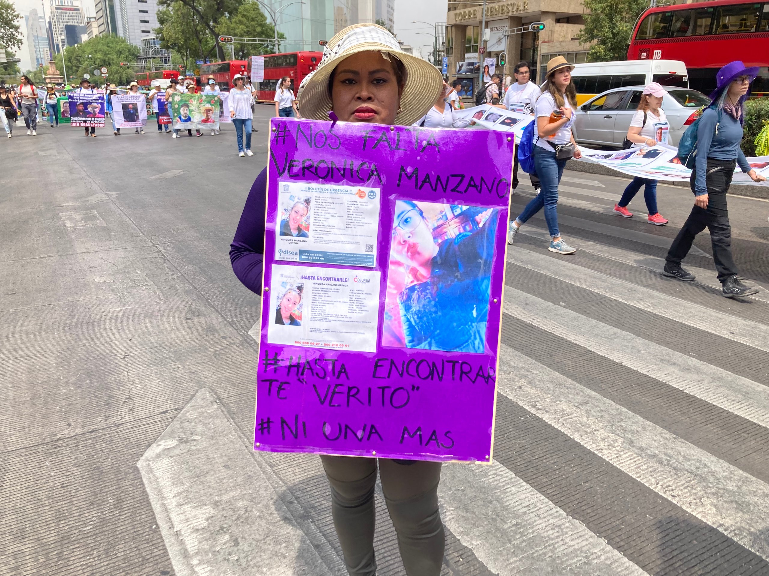 A woman holds up a purple sign during a protest in Mexico City for her disappeared family member.