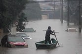 A man rows a small boat down a flooded street in Brazil.