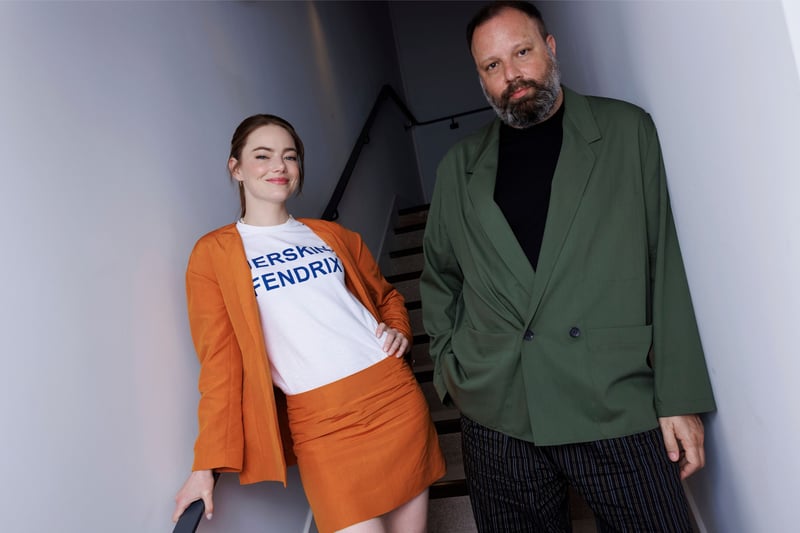 Emma Stone and Yorgos Lanthimos pose for a photo on a staircase.