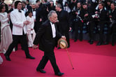 Francis Ford Coppola uses a cain to walk along the red carpet outside the Cannes film festival.