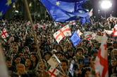 Protesters wave EU and Georgian flags.