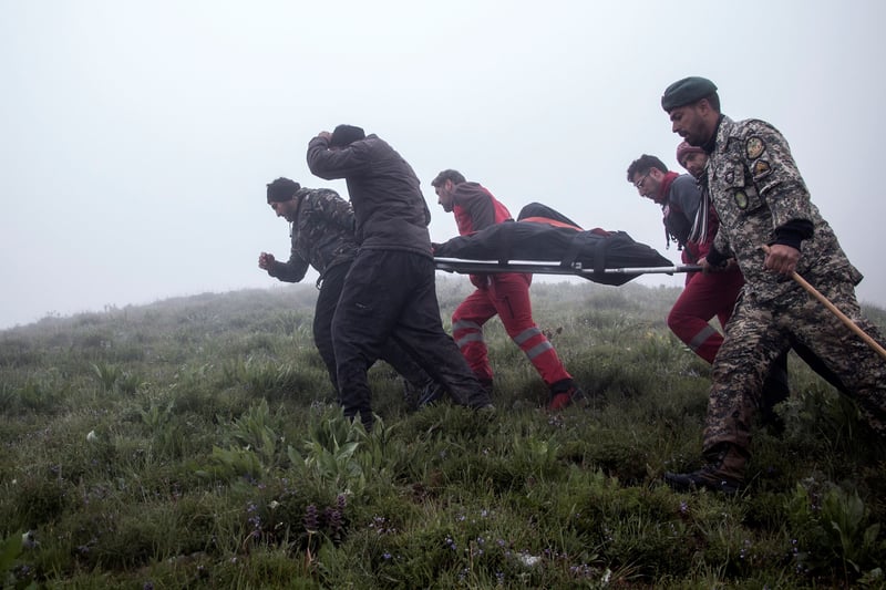 People carry a body on a stretcher in the fog.