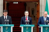 Three Irish leaders stand at podiums at a news conference.