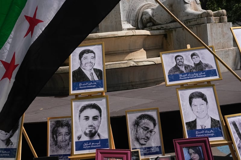Portraits of Mazzen Dabbagh, Patrick Dabbagh and others below a Syrian flag.