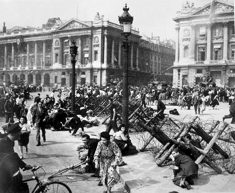 Parisians celebrating liberation during World War II cower under fire.