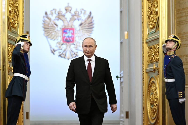 Vladimir Putin walks between two guards opening doors.