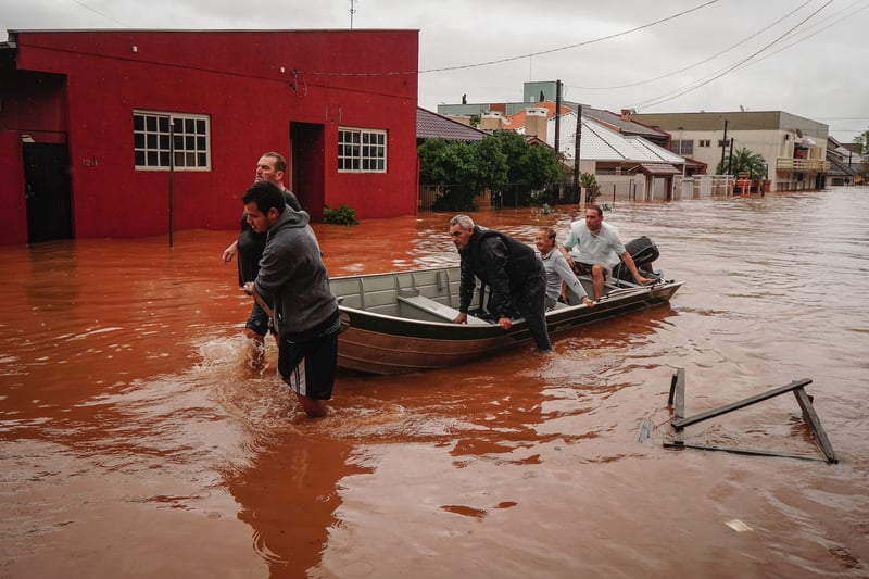 Two people steer a canoe with three people on it through a flooded area in São Sebastião do Caí, Brazil.