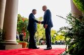 Xi Jinping shakes hands with Joe Biden as they stand on a red carpet.