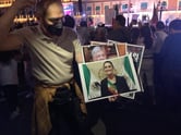 A man in a white shirt holds pictures of Claudia Sheinbaum in the Zocalo in Mexico City.