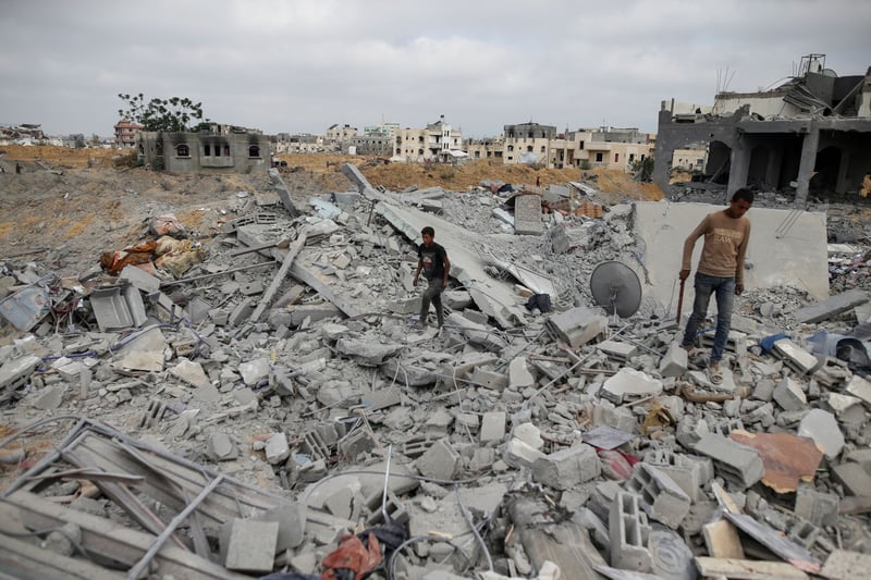 People walk on rubble from destroyed buildings.