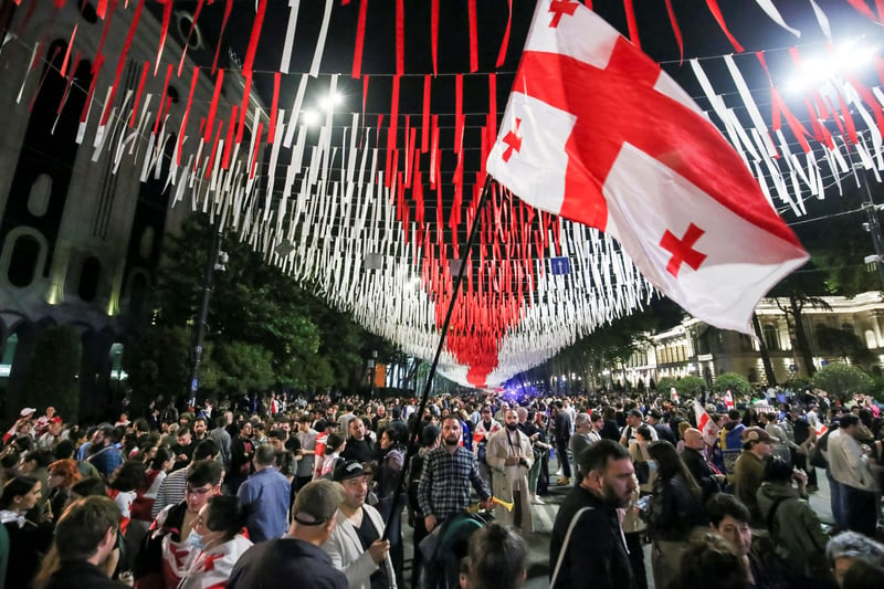 A crowd mills about under red-and-white streamers and a Georgian flag.