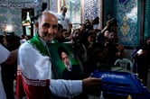 An Iranian man holds a photo of Ebrahim Raisi as he prepares to cast his ballot.