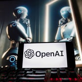 The Open AI logo on a phone in front of an image of a robotic figure gazing at its reflection.