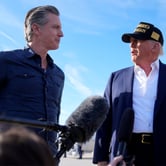 Gavin Newsom and Donald Trump stand side by side with a boom mic in between them.