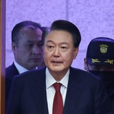 An older man in a suit enters a doorway.