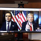 Todd Blanche and Donald Trump, pointing, have two American flags between them as they appear on a video monitor at Trump's hush money sentencing.