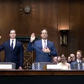 Four men in suits standing behind a desk, each with their right arm held up, swearing an oath.