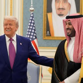 Trump pats Mohammed bin Salman on the back as they smile. A U.S. flag and portrait of a man hang behind them.
