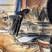 Sean Diddy Combs wears a brown suit jacket as he sits at a table and looks to the right.