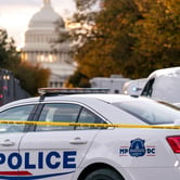 A white police cruiser behind yellow crime scene tape in front of the U.S. Capitol.