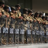 California National Guard troops stand in formation holding shields.