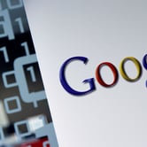 The Google logo on a white wall next to a glass panel