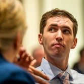 Man in shirt and tie listens during discussion