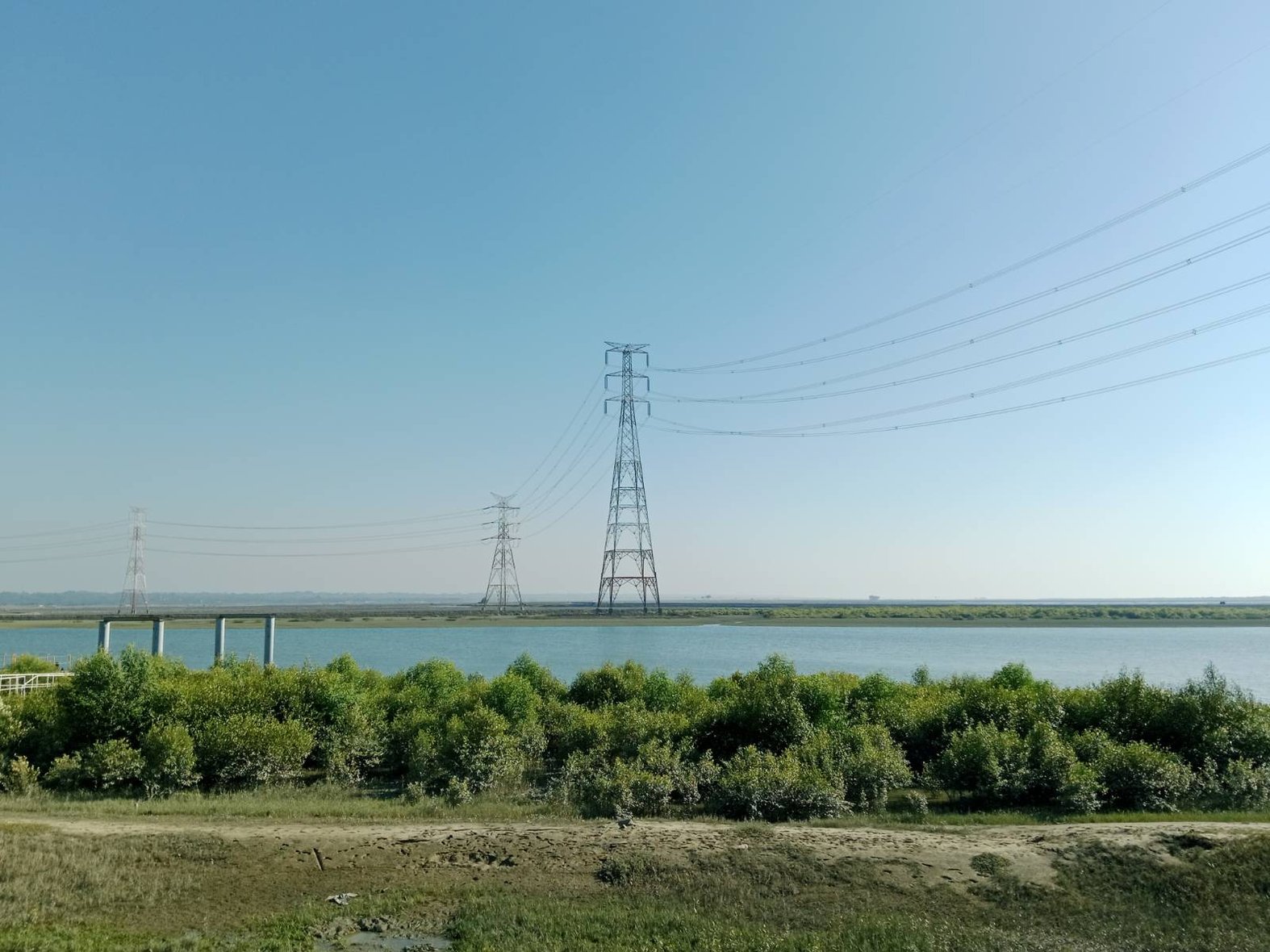 (Above) Power lines from the Matarbari power plant running across the Kohelia river. (Right)  People of Moheshkhali gathered at a Madrassa (an Islamic school) raising concerns about land acquisition for the mega project. Photos by: Rishika Pardikar