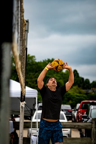 A player in black reaches overhead for the ball.