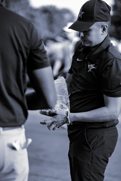 A player in a dark shirt and cap holds a plastic bag.