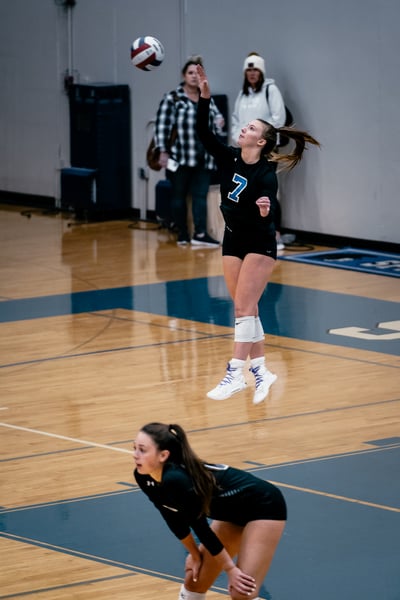 A player in black jumps and reaches for the ball.
