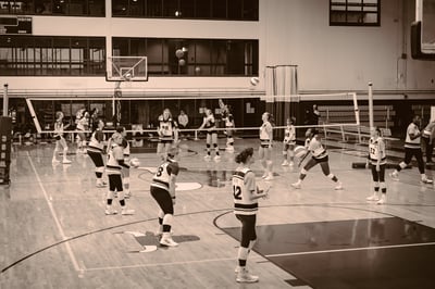 A player in black and white extends her arm to hit the ball over the net.