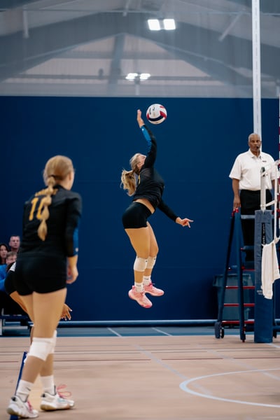 A player in black jumps and reaches for the ball.