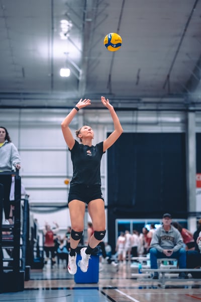 A player in black jumps with arms extended toward the ball.