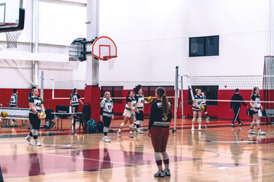 A player in green and white holds a ball while standing on a court.