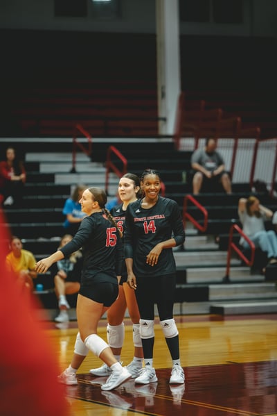 A North Central player in black stands with hands open on a court.
