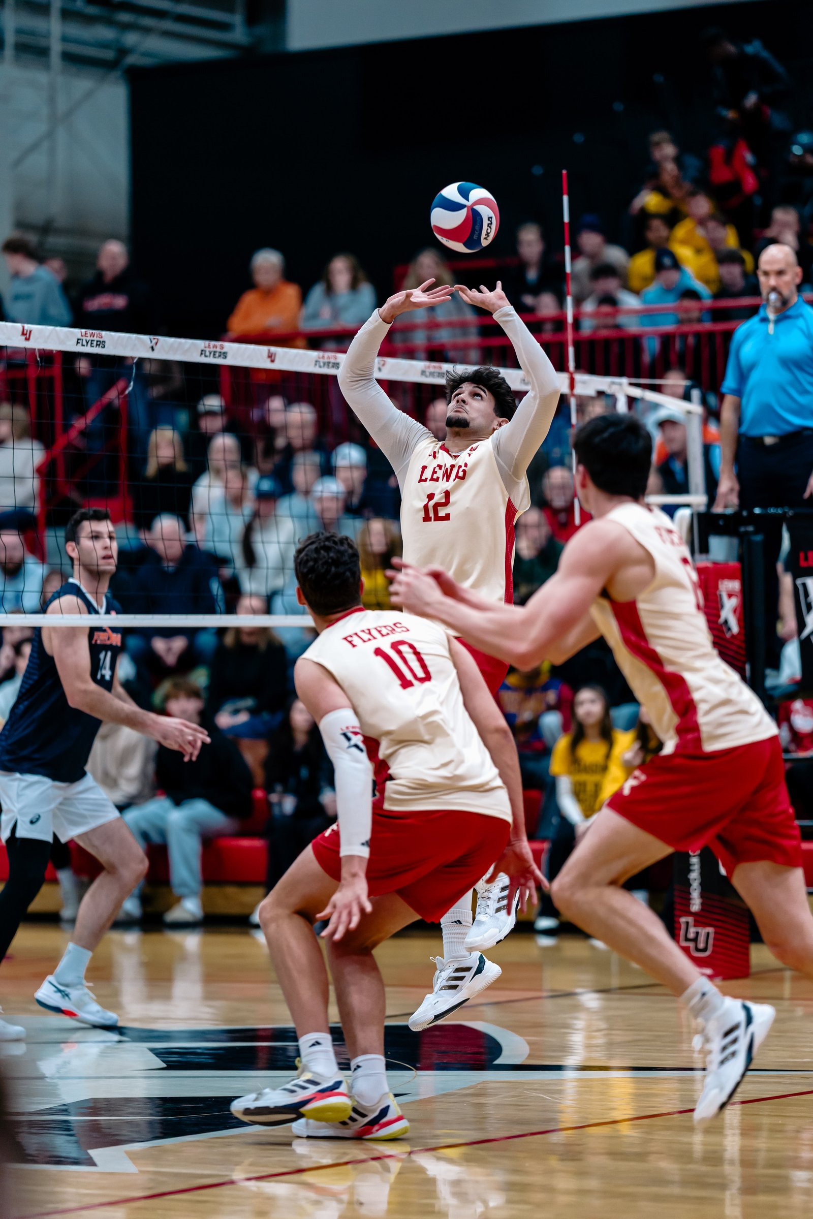 A volleyball player in a white and red jersey with number 12 sets the ball during a game.