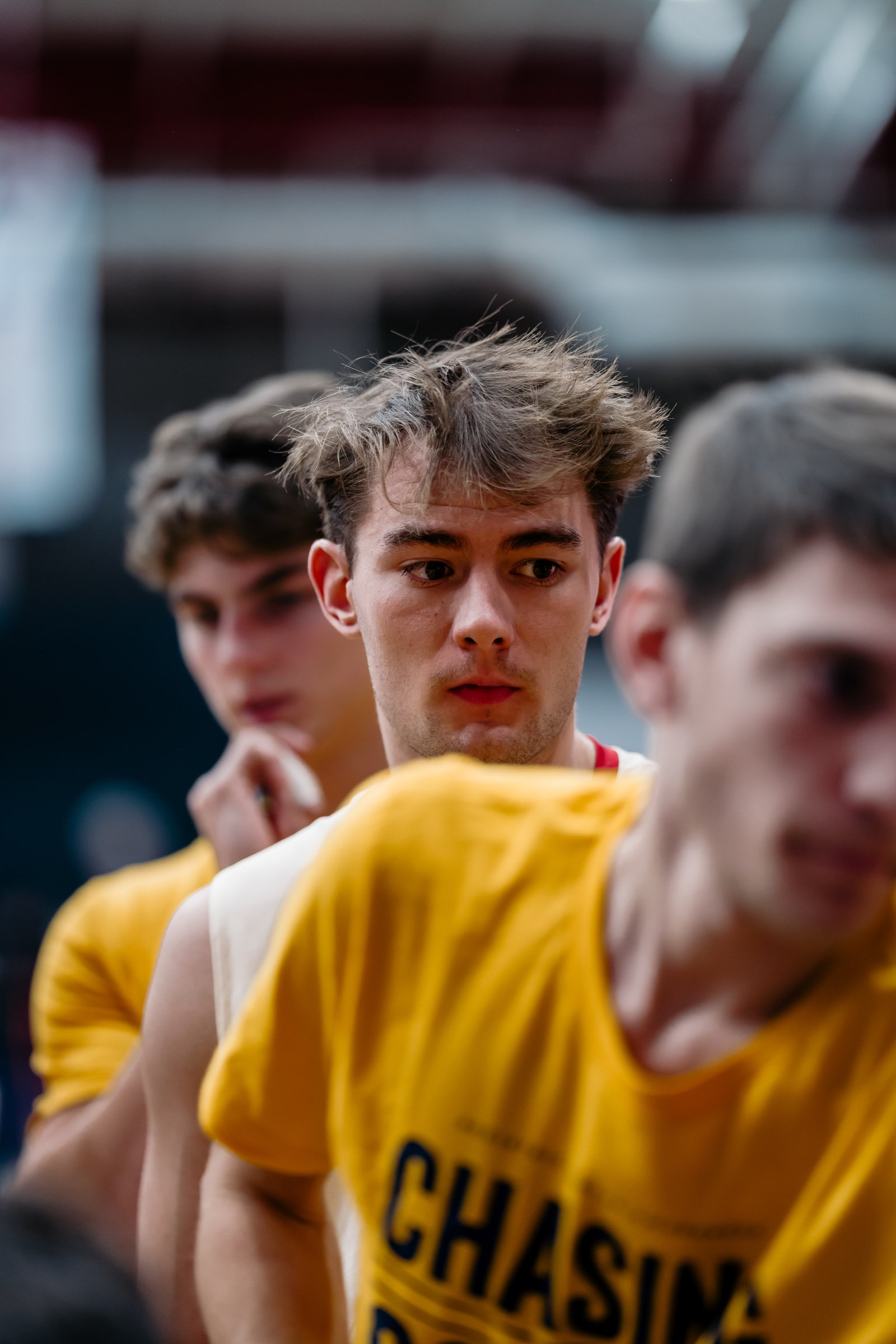 Players in yellow jerseys look on during a volleyball match.